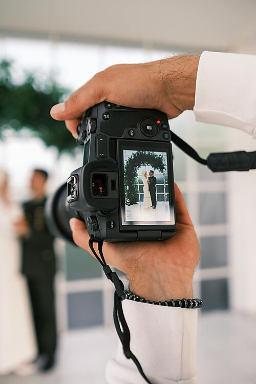 Frau fotografiert eine Gruppe von Männern – Symbolbild für das Auswählen eines passenden Familien- oder Hochzeitsfotos für ein personalisiertes Malen-nach-Zahlen-Set.