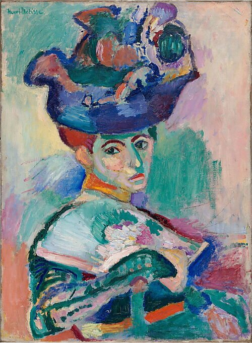 Eine sitzende Frau mit großem farbigem Hut blickt aus dem Halbprofil nach vorn; ihr Gesicht ist in Grün, Gelb, Rosa und Violett gemalt.