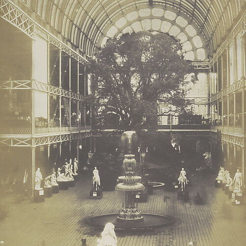 Blick durch die hohe, verglaste Querhalle des Crystal Palace; im Vordergrund stehen ein Brunnen und Skulpturen, dahinter ein großer Baum.