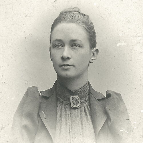 Historisches Schwarz-Weiß-Porträt der jungen Hilma af Klint mit hochgestecktem Haar und einer Brosche am geschlossenen Kragen.