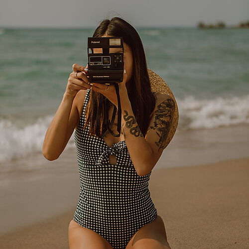 Frau mit Polaroidkamera am Strand
