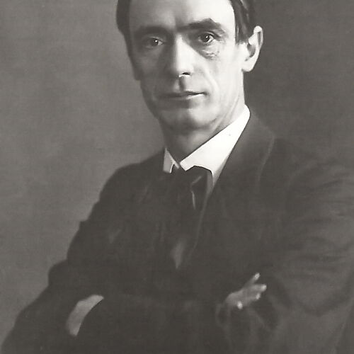 Schwarzweißporträt Rudolf Steiners um 1905; er sitzt im dunklen Anzug mit verschränkten Armen und blickt in die Kamera.