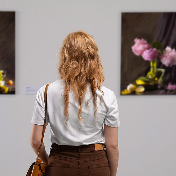 Frau, in einer Ausstellung Bilder betrachtend