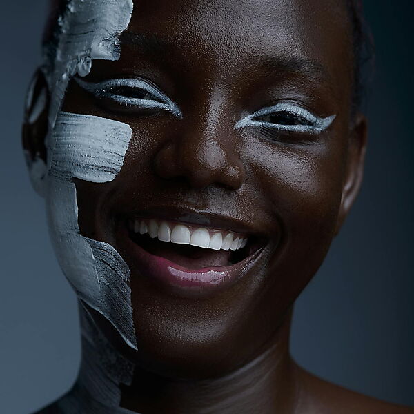 Lachende Frau mit weißer Farbe im Gesicht