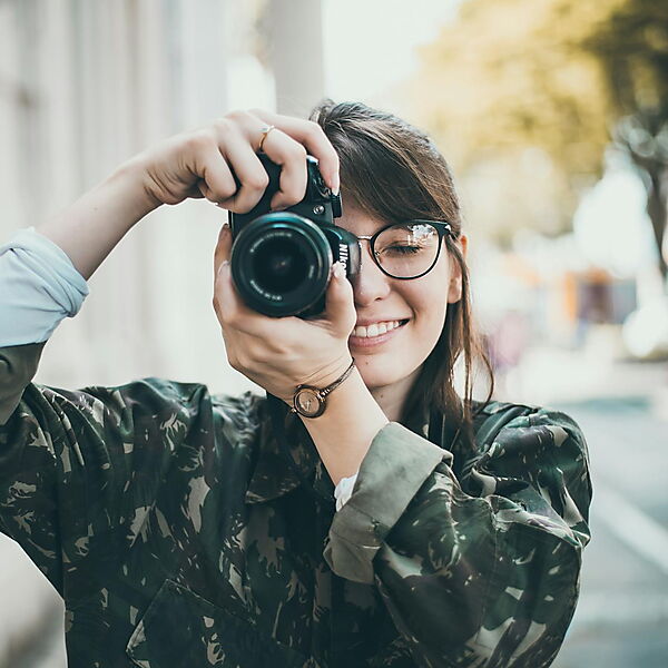 Frau fotografiert mit einer DSLR-Kamera – Symbolbild für Fotoauswahl und Vorbereitung, um typische Fehler bei Malen-nach-Zahlen-Foto-Sets zu vermeiden.