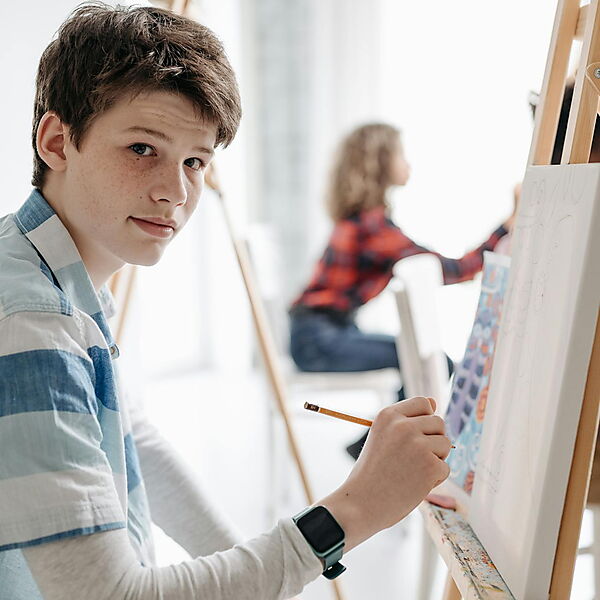 Junge Mann hält einen Bleistift – Symbolbild für Zeitplanung und realistischen Zeitaufwand beim Malen nach Zahlen.