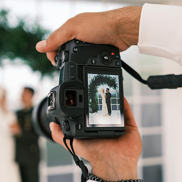 Frau fotografiert eine Gruppe von Männern – Symbolbild für das Auswählen eines passenden Familien- oder Hochzeitsfotos für ein personalisiertes Malen-nach-Zahlen-Set.