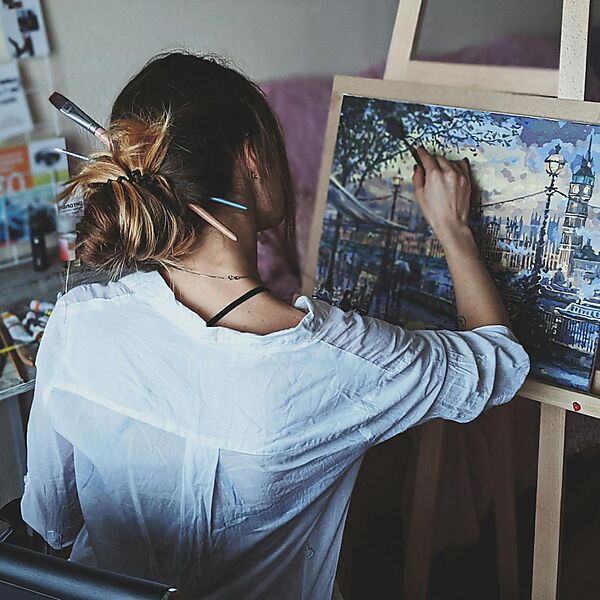 Frau steht vor einer großen Leinwand und betrachtet ein Gemälde – Symbolbild für Formatwahl und Bildgröße beim Malen.