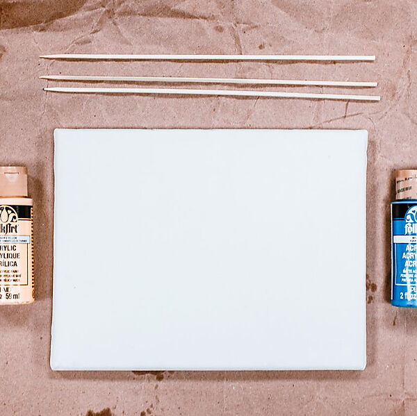 Acrylfarben, Pinsel und ein leerer Malgrund liegen als einfache Starter-Ausstattung bereit