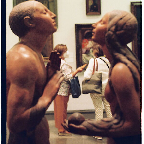 Zwei Besucherinnen betrachten gemeinsam die Skulptur „Adam und Eva“ in einem Kunstmuseum in Lissabon.