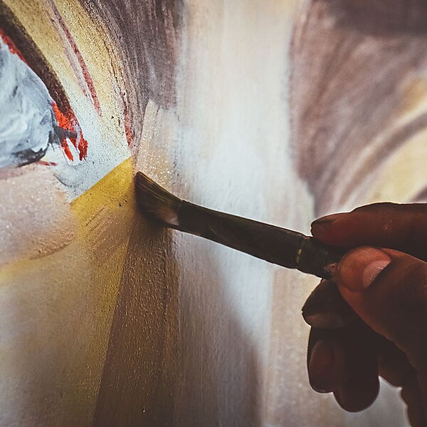 Hand überarbeitet mit einem Pinsel eine bereits bemalte Acrylfläche auf Leinwand.