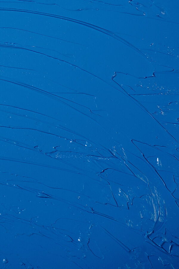 Ungleichmäßiger blauer Acrylauftrag mit sichtbaren Flecken und Pinselspuren auf hellem Untergrund.