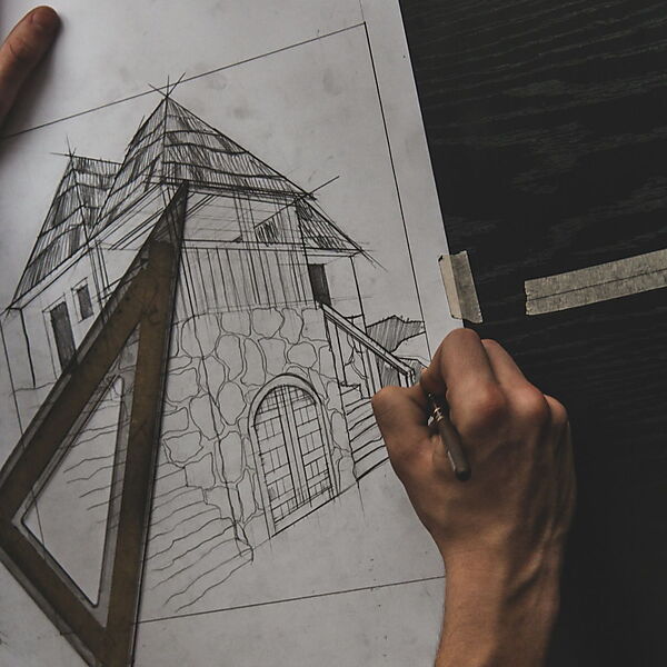 Hand zeichnet mit Bleistift und Lineal ein Haus auf Papier und prüft dabei Linien, Winkel und Perspektive.