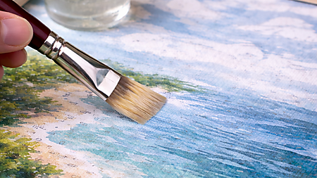 Nahaufnahme: Pinsel trägt von links eine transparente Versiegelung auf ein fertiges Malen-nach-Zahlen-Bild auf; Farbtöpfe und ein Glas mit Klarlack stehen im Hintergrund.