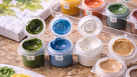 Nahaufnahme von geöffneten Farbtöpfchen mit Acrylfarben neben einer Malen-nach-Zahlen-Leinwand und einer Mischpalette – Symbolbild für Deckkraft, Konsistenz und typische Farbprobleme im Set.