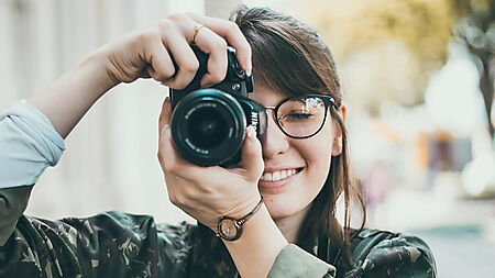 Frau fotografiert mit einer DSLR-Kamera – Symbolbild für Fotoauswahl und Vorbereitung, um typische Fehler bei Malen-nach-Zahlen-Foto-Sets zu vermeiden.