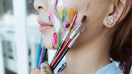 Nahaufnahme einer Hand mit bunten Farben – Symbolbild für einen kreativen Einstieg ins Malen nach Zahlen.