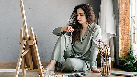 Frau sitzt am Tisch und malt konzentriert – Symbolbild für das Einschätzen von Detailgrad und Aufwand beim Malen nach Zahlen.