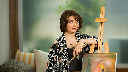 Frau präsentiert ein Kunstwerk in einer Ausstellung – Symbolbild für Leserbeiträge, Teilen und Community rund um Malen nach Zahlen.