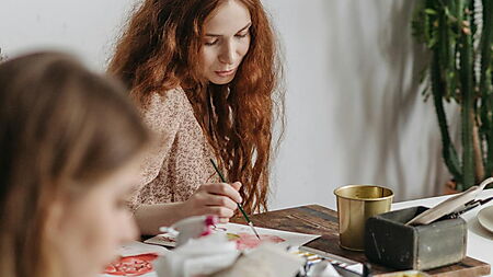 Frau arbeitet in einer Werkstatt an einem Malprojekt – Symbolbild für die Entwicklung von Malen nach Zahlen vom klassischen Set zur modernen, personalisierten Variante.