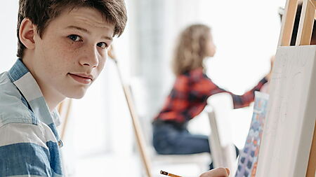 Junge Mann hält einen Bleistift – Symbolbild für Zeitplanung und realistischen Zeitaufwand beim Malen nach Zahlen.