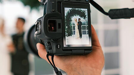 Frau fotografiert eine Gruppe von Männern – Symbolbild für das Auswählen eines passenden Familien- oder Hochzeitsfotos für ein personalisiertes Malen-nach-Zahlen-Set.