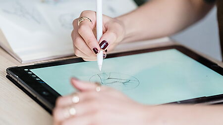 Frau arbeitet kreativ an einem digitalen Arbeitsplatz und verbindet Gestaltung mit moderner Zeichentechnik.