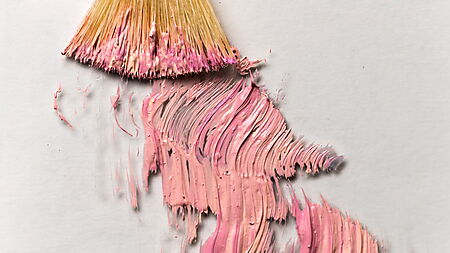 Ein Pinsel zieht rosa Acrylfarbe in sichtbaren Spuren über eine helle Leinwand