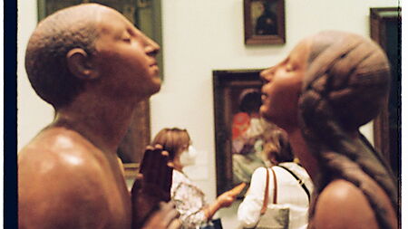 Zwei Besucherinnen betrachten gemeinsam die Skulptur „Adam und Eva“ in einem Kunstmuseum in Lissabon.