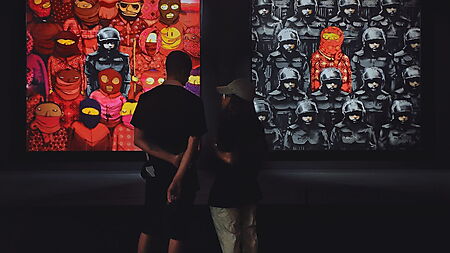 Zwei Personen betrachten unterschiedliche Gemälde in einer Galerie und prüfen ihre Wirkung, bevor sie das Bild deuten.