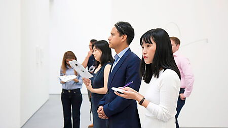 Mehrere Menschen betrachten gemeinsam Kunstwerke in einem modernen Museum.