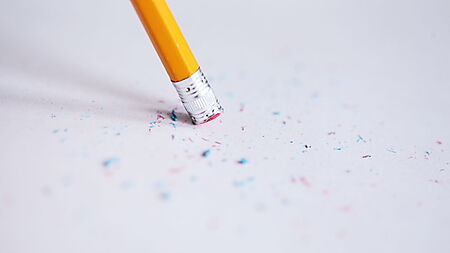 Bleistift radiert auf Papier und zeigt Radierkrümel als normalen Teil des Zeichenprozesses.