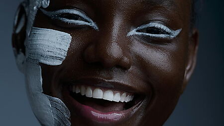 Lachende Frau mit weißer Farbe im Gesicht