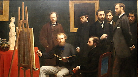 Acht dunkel gekleidete Männer versammeln sich in einem Atelier um Édouard Manet, der mit Palette und Pinsel vor einer Staffelei sitzt.