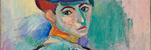 Eine sitzende Frau mit großem farbigem Hut blickt aus dem Halbprofil nach vorn; ihr Gesicht ist in Grün, Gelb, Rosa und Violett gemalt.