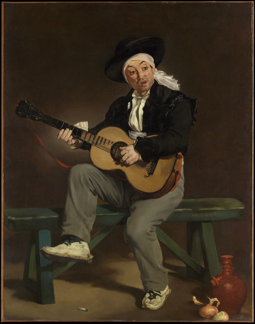 Ein sitzender Mann in spanisch anmutender Kleidung spielt Gitarre vor einem dunklen Hintergrund.